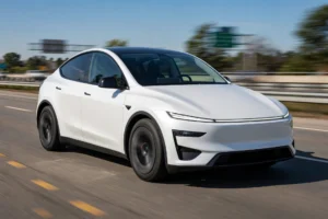 White 2026 Tesla Model Y Juniper on a highway at golden hour during a Tesla Model Y speed range test