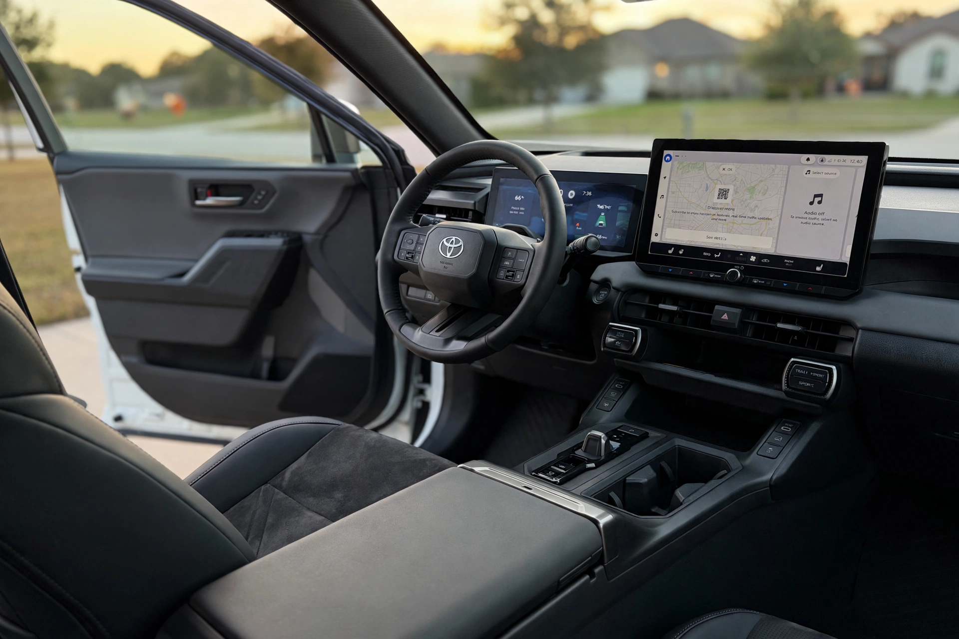 Cabin of a 2026 toyota rav electric plug-in hybrid showing SofTex and suede seats, a 12.9-inch touchscreen and the layered dashboard in evening light